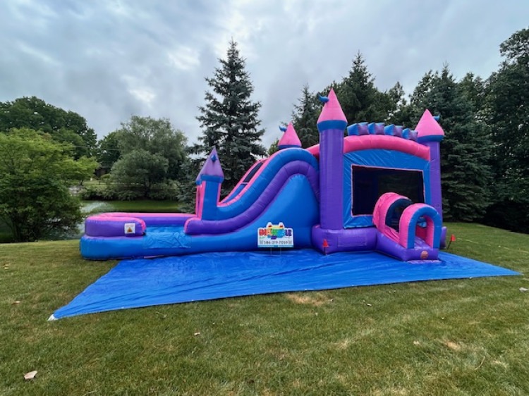 Blue and purple inflatable water slide rental setup at an outdoor event